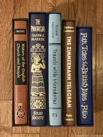 All five slipcases upright on wood floor showing spines and titles