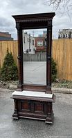 Full front view of pier mirror showing marble top, mirror and storage cupboard base