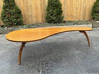 Front view showing full tabletop shape and three splayed legs on pavement