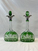 Pair of green overlay glass decanters with silver collars displayed front view