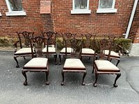 Front view of complete set of 8 chairs including 2 armchairs and 6 side chairs, arranged in two rows outdoors.