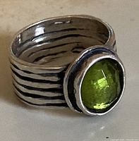 Close-up of the sterling silver modernist ring showing green gemstone and textured band