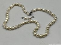 Pearl necklace and stud earrings laid out showing pearls and clasp details