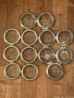 All 13 coasters arranged on floor, mix of three rim patterns and crystal cuts