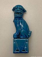 Front view of the turquoise blue glazed porcelain lion foo dog figurine sitting on a rectangular base.