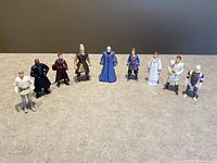 Full lot of 9 Star Wars figures arranged in a line on gray surface, showing the variety of characters from the Star Wars saga.