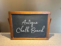 Front view of antique slate chalk board with wood frame showing writing 'Antique Chalk Board' on surface.