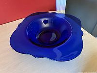 Top-side angled photo highlighting the wide, scalloped rim and deep blue color of the glass bowl.