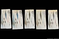 Five vintage MCM atomic design fabric panels laid side by side, showing front designs of diamond and starburst shapes in muted tones on a beige base.