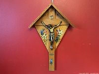 Front view of wooden crucifix with metal figure, floral painted decoration, and PUCHHEIM plate