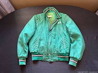 Front view of vintage green farming jacket with Pioneer Seeds patch on left chest, heavy metal zipper, snap buttons, ribbed cuffs and waistband with stripe detail.