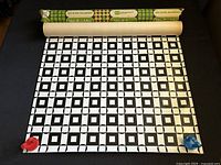 Vintage Wall-O-Vin vinyl wall covering roll partially unrolled showing black and white geometric pattern.
