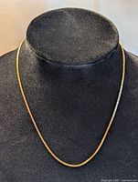 Front view of gold necklace displayed on black velvet bust