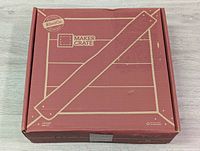 Top view of closed Kiwi Co Maker Crate box with stencil style printed book holder parts on lid, showing the package contents are unopened and new condition.