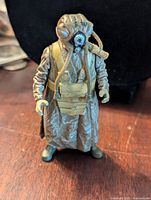 Frontal photo of the Kenner Star Wars Zuckuss figure standing on a wooden surface with complete costume showing mask, tubes, and boots.