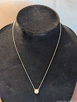 Full necklace on display stand showing fine silver chain and cat pearl pendant.