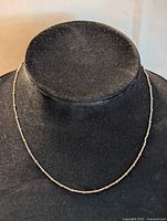 Full view of delicate sterling silver station necklace with tiny beads along chain on black display stand