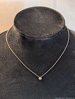 Front view of sterling silver necklace with cubic zirconia pendant on a black display stand, showing fine chain and clear round stone pendant.