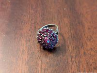 Top view of the sterling silver ring showing pink cluster gemstones arranged in a floral pattern on wooden surface.