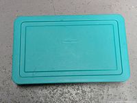 Top view of the turquoise colored Rubbermaid plastic storage box showing the lid with brand name embossed and no visible cracks.