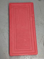 Top view of red plastic storage container lid showing its textured surface and rectangular shape.
