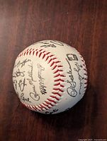 Commemorative baseball showing printed signatures arranged clearly and evenly across the white surface with red stitching, capturing team member names and signature styles.