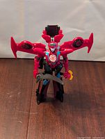 Front view of Windblade robot figure holding sword accessory with red wings and blue face details.