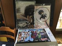Two anime prints, one from Attack on Titan featuring a Titan character close-up and one from Naruto showing a group of characters, plus an anime handheld fan in plastic packaging.