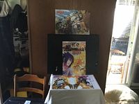 Three Naruto-themed anime prints arranged on a chair and table against a wall.