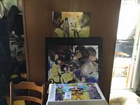 Four Naruto anime prints, two close-up character portraits (Sasuke and Itachi) in one print and multi-character prints displayed against wooden background.