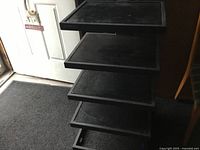 Photo showing the tiered design and black wood shelving with metal frame.