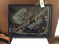 Shadow box containing vintage Indigenous artifacts including a bandolier belt, wrist cuffs, a pouch, and beaded ornament.