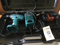 View of Makita cordless drill, battery, and charger inside the hard plastic carrying case, showing overall condition and organization.