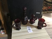 Four dark red Avon bubble bath decanter bottles on a wooden surface with a black background.