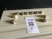 Image shows a semi-circle arrangement of 10 used playoff rings laid out on a light wood surface with a MaxSold card in the center