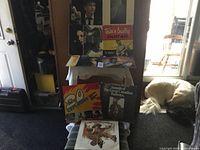 Full lot of 10 vinyl records displayed on tables and chair, some albums stacked, dog visible in background.