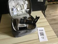 Closed soft carrying case opened showing telescope attachment, clip mount, lens cap, and paperwork inside.