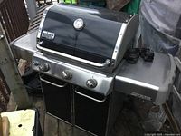 Front and angled view of Weber Genesis grill with lid closed, showing stainless steel control panel and brand badge