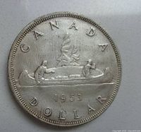 Front side of 1953 Canada silver dollar showing two voyageurs paddling a canoe with cargo.