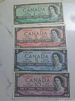 Four Canadian banknotes from 1954 in very good condition showing $1, $2, $5, and $10 denominations.