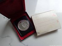 1976 Canadian silver dollar coin in display case with accompanying envelope.