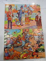 Photo showing one Disney puzzle with characters including a British guard, policeman, and Disney figures like Mickey and Goofy, assembled and complete