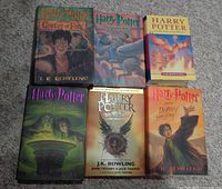 Six Harry Potter books arranged in two rows of three on a gray surface. Covers show illustrations specific to each book title.