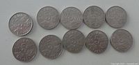 Ten coins laid out on white surface (actual lot of eight)