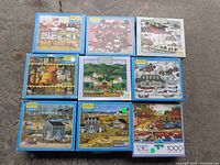 Nine Charles Wysocki puzzle boxes arranged in a 3x3 grid showing various colorful Americana farm and village artwork. Boxes are in generally good visible condition.