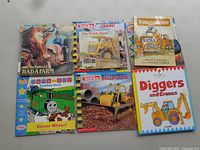 Front covers of six boys' books featuring trucks, construction vehicles, and children's characters like Thomas the Tank Engine and Tonka.