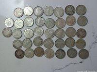 Photo showing 39 Canadian silver dimes arranged in rows on a white surface, exhibiting various degrees of wear and patina.