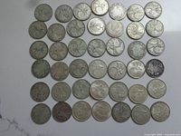 Overhead view of 51 Canadian silver quarters laid out on white surface
