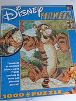 Photo of puzzle box showing Disney Photomosaics 1000-piece puzzle featuring Tigger with text describing thousands of miniature Disney movie frames combined into one portrait.