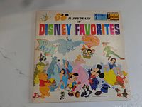 Front cover of the '50 Happy Years of Disney Favorites' vinyl record album featuring various classic Disney characters in colorful artwork.